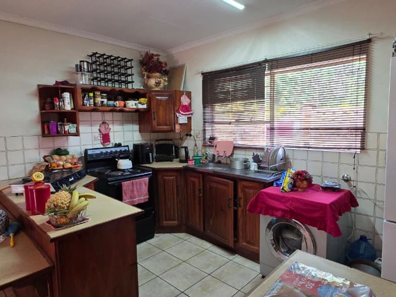 A functional kitchen featuring wooden cabinetry, tiled backsplash, and built-in stove, offering a practical layout with potential for modern cosmetic updates.