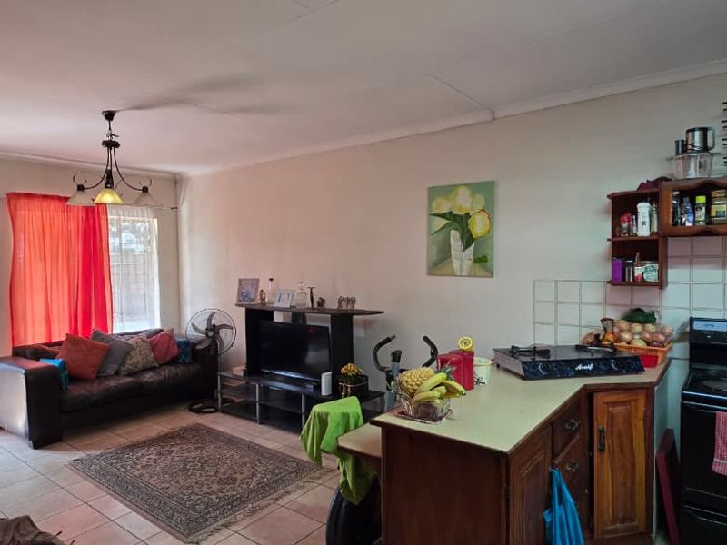 Open-plan living and kitchen area featuring tiled flooring, built-in cabinetry, and direct access to the garden through a sliding glass door.
