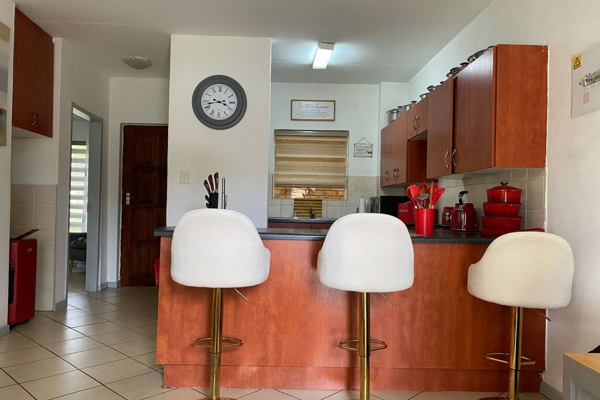 A functional kitchen featuring laminate cabinetry, a breakfast bar, and tiled flooring, offering a practical layout for daily meal preparation.