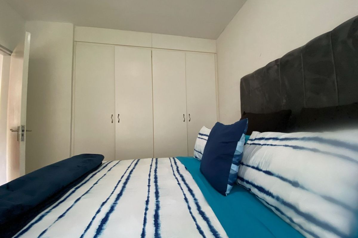 A bedroom featuring white built-in cupboards and neutral wall finishes.