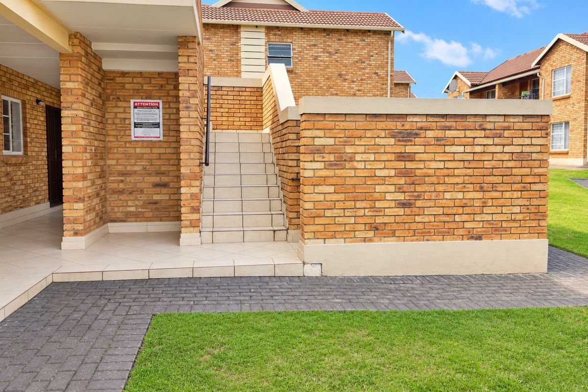 Exterior view of a face brick residential building featuring a tiled staircase, paved walkway, and well-maintained lawn area.