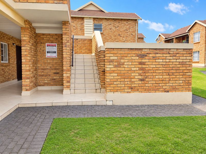 Exterior view of a face brick residential building featuring a tiled staircase, paved walkway, and well-maintained lawn area.
