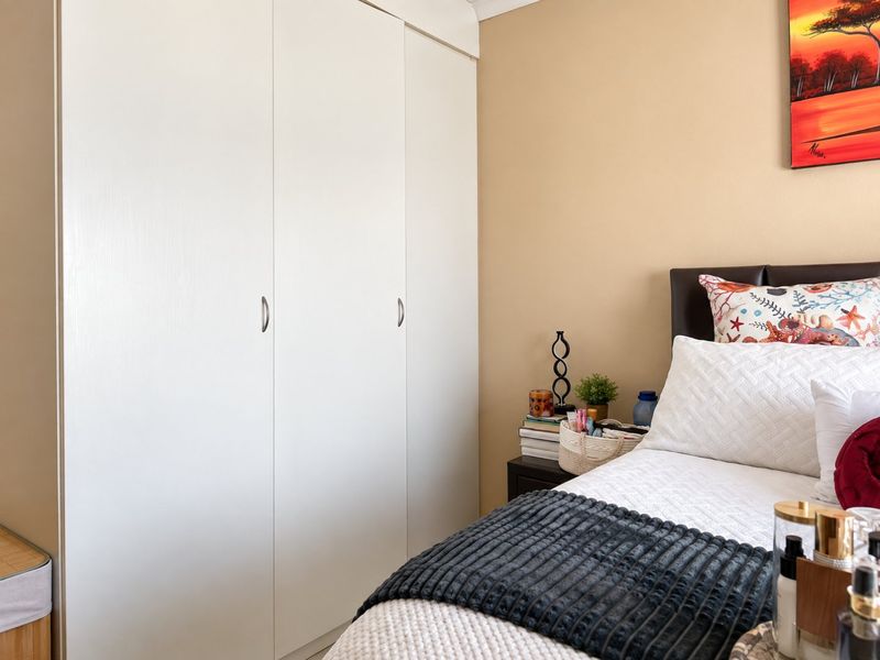 A well-maintained bedroom featuring clean, white built-in cupboards and neutral wall tones.