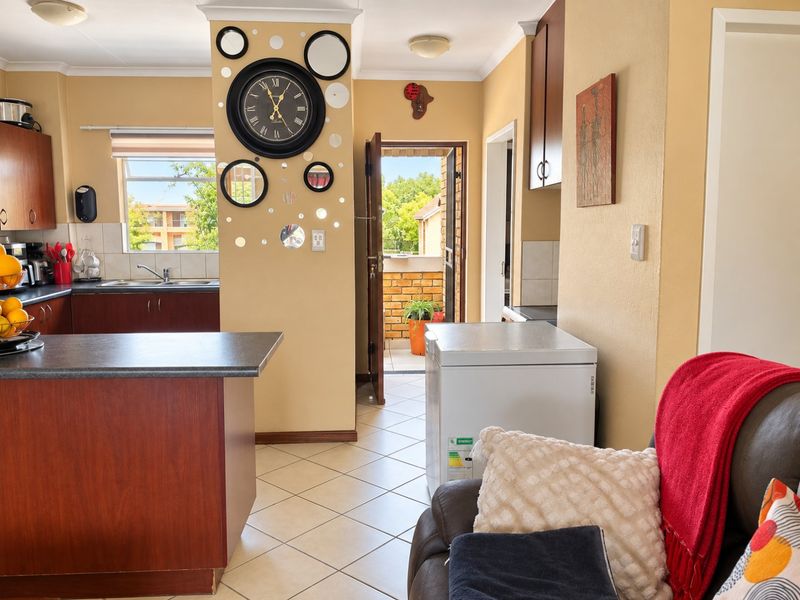 Open plan kitchen area featuring dark wood cabinetry, laminate countertops, and tiled flooring, with direct access to an outdoor balcony area.