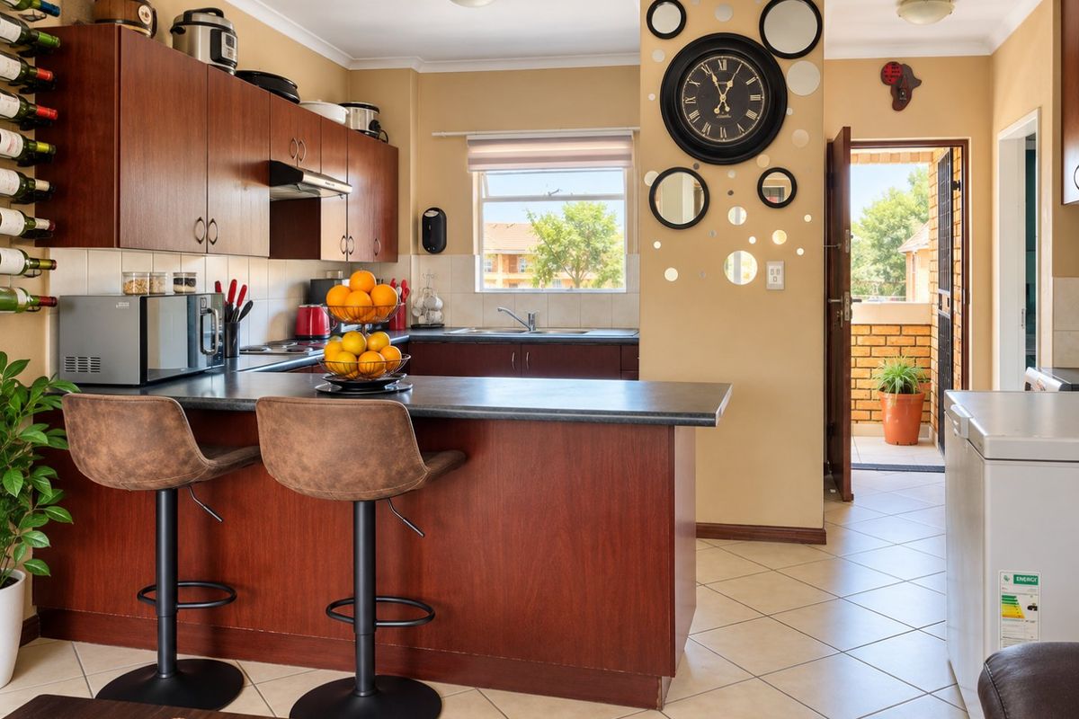 A functional kitchen featuring dark wood-look cabinetry, laminate countertops, a breakfast bar, and tiled flooring with direct access to an outdoor area.