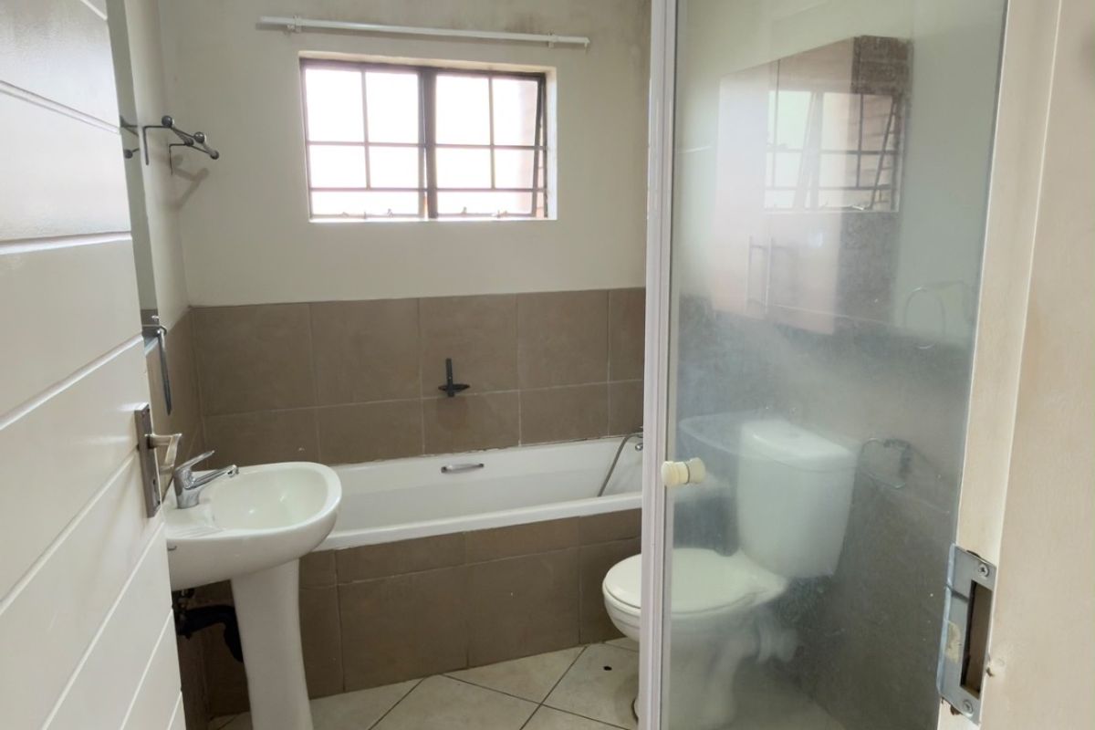 A functional bathroom featuring a pedestal basin, bathtub, and separate shower enclosure with tiled finishes, ready for a modern update.