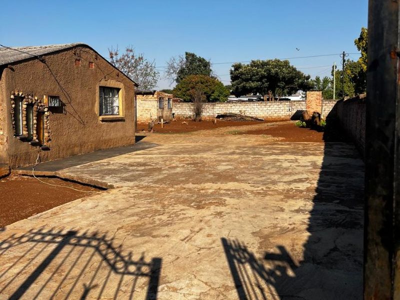A view of the front exterior featuring a concrete driveway, perimeter wall, and metal gate entrance to the property.