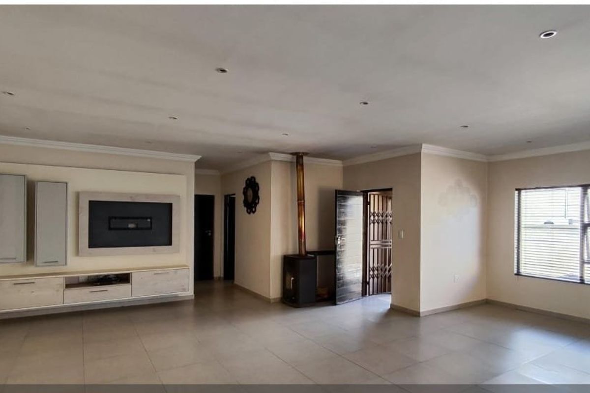 Spacious living area featuring large format floor tiles, a built-in media console, and a freestanding fireplace, offering a versatile open-plan layout.