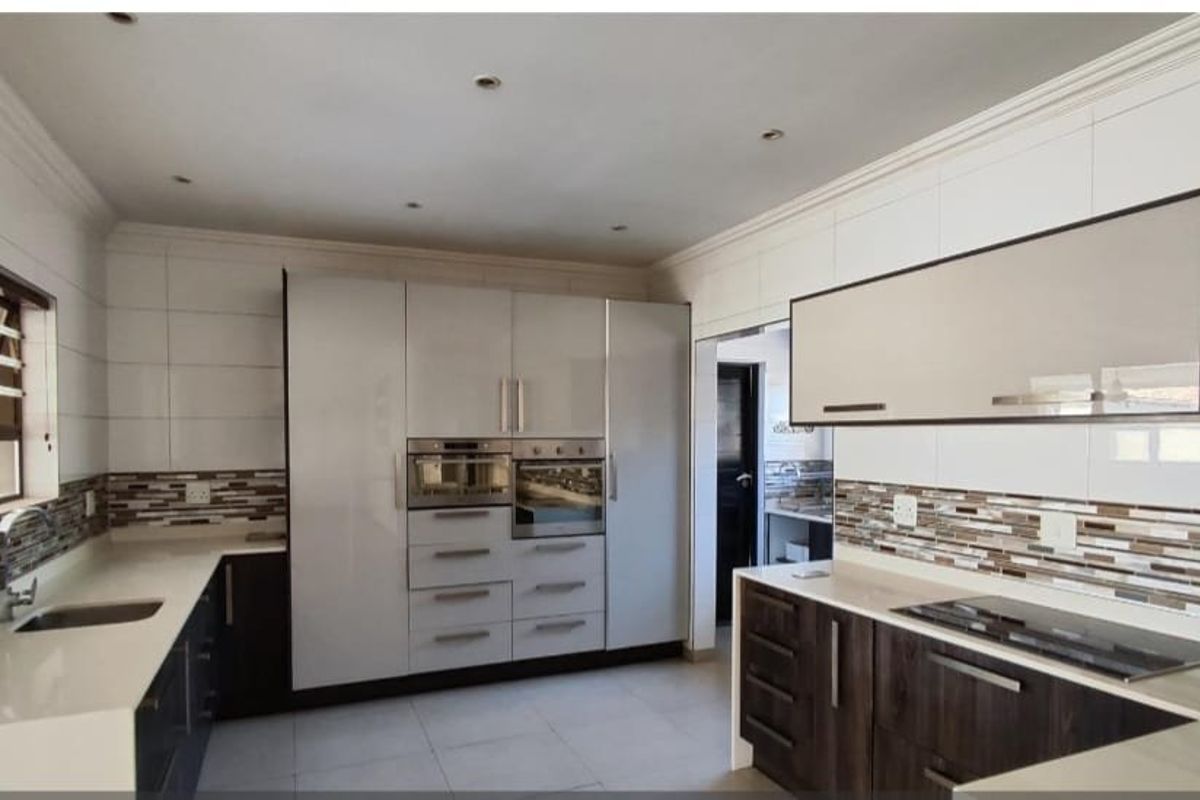 Modern kitchen featuring high-gloss cabinetry, quartz countertops, integrated appliances, and a stylish mosaic tiled backsplash with ample workspace.
