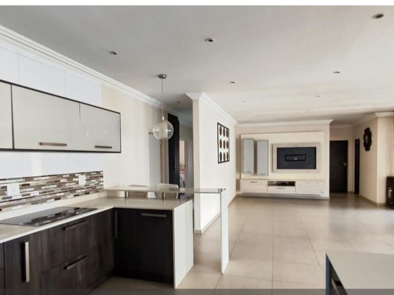 Spacious open-plan living area featuring a modern kitchen with stone countertops, built-in cabinetry, and a seamless flow to the lounge with a fireplace.