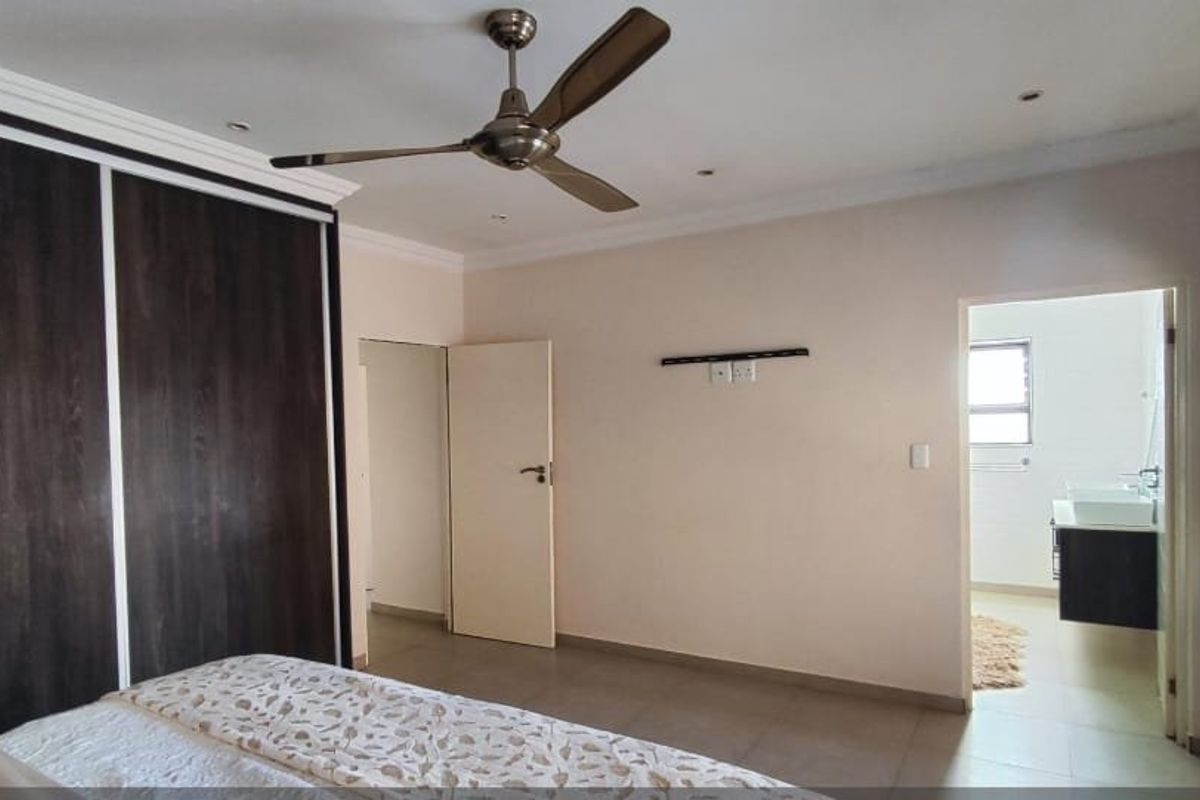 Spacious bedroom featuring built-in cupboards, a ceiling fan, recessed lighting, and an en-suite bathroom with modern vanity.