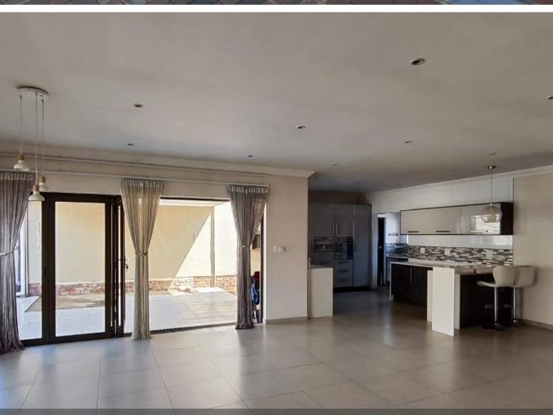 Spacious open-plan living area featuring tiled floors, recessed lighting, and a modern kitchen with built-in cabinetry, island, and direct access to the patio.