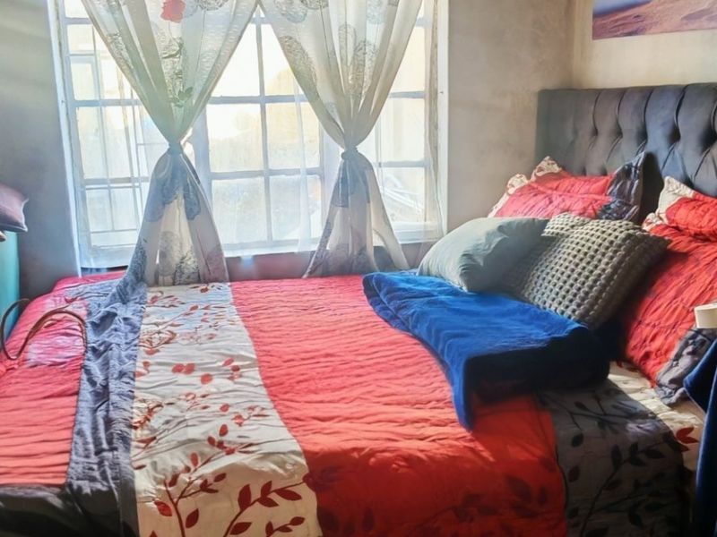 A bedroom featuring a grid-pattern window and unfinished wall surfaces, requiring cosmetic updates to improve the overall finish and condition.