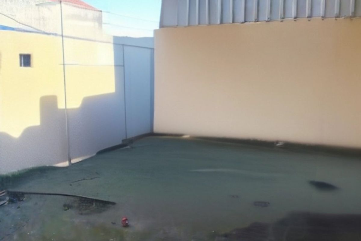 Rear exterior view of the apartment building showing a paved courtyard area, balcony railing, and satellite dish installation.