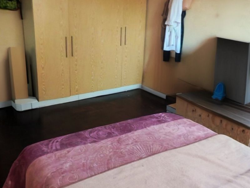 Bedroom featuring built-in wooden cupboards and a picture rail, requiring ceiling repairs and cosmetic updates to improve the overall condition.