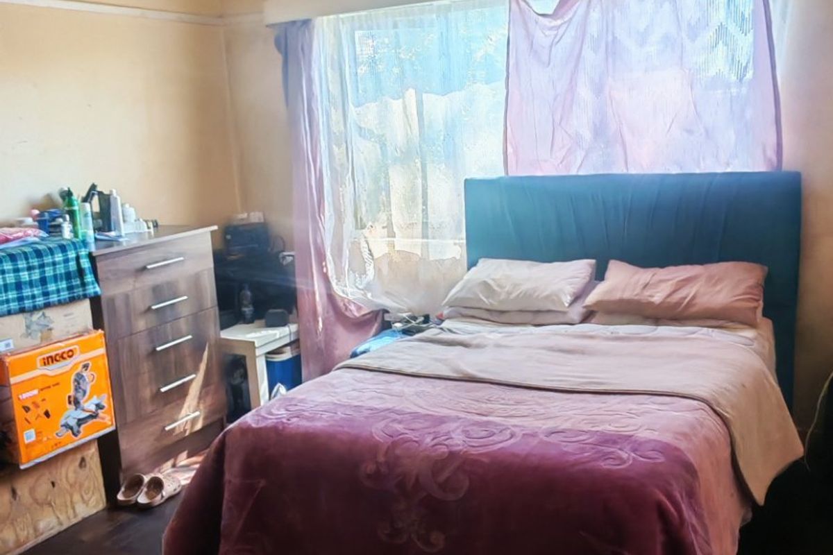 A bedroom featuring hardwood flooring and a coved ceiling, currently requiring significant cosmetic updates to the walls and ceiling finishes.