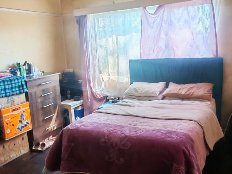 A bedroom featuring hardwood flooring and a coved ceiling, currently requiring significant cosmetic updates to the walls and ceiling finishes.