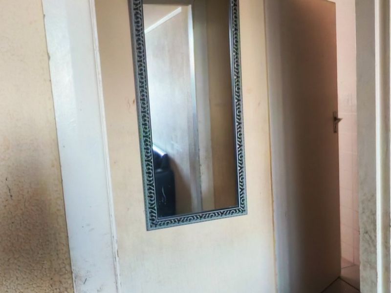 A narrow hallway entrance showing signs of wear on the door frame and surrounding wall surfaces, requiring maintenance and cosmetic updates.
