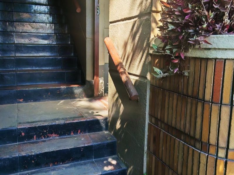 Exterior entrance featuring a tiled staircase with a handrail and decorative brick facade cladding.