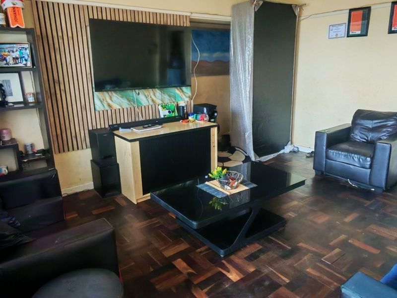 Living room featuring dark parquet flooring and a decorative slatted wood feature wall, requiring cosmetic updates to improve the overall aesthetic.