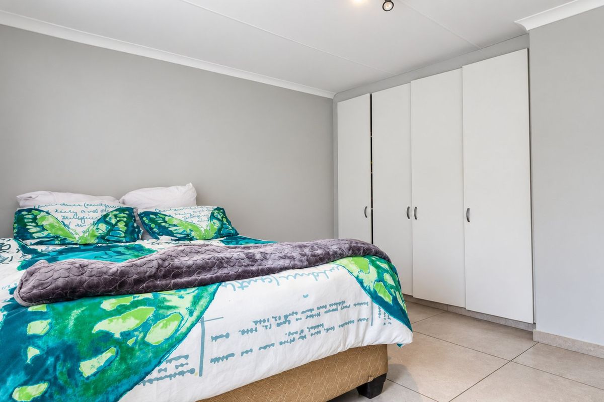 A well-maintained bedroom featuring neutral wall tones, tiled flooring, and ample built-in cupboard storage.