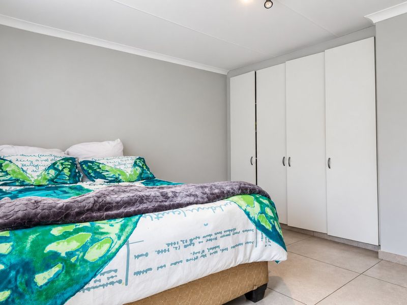 A well-maintained bedroom featuring neutral wall tones, tiled flooring, and ample built-in cupboard storage.