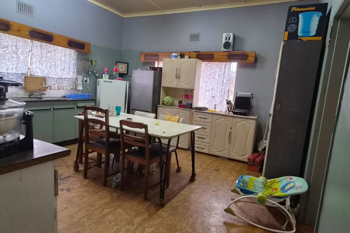 A dated kitchen area featuring built-in cabinetry, a sink, and tiled splashbacks, offering significant potential for modernization and renovation.