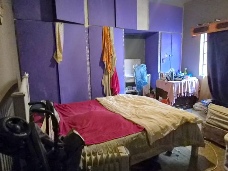 A bedroom featuring built-in purple cabinetry and a window, currently requiring cosmetic updates to improve the overall finish and aesthetic appeal.