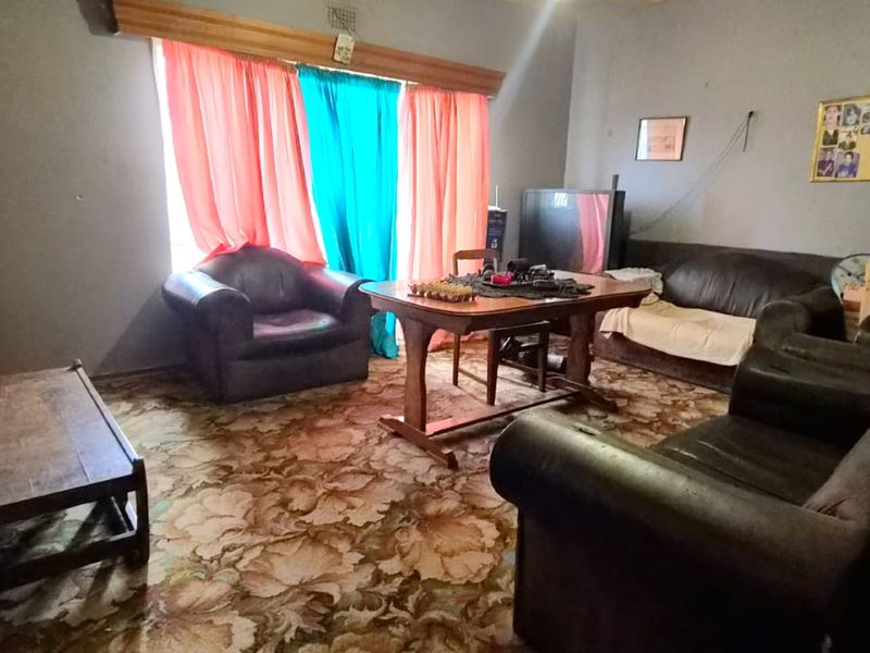 A living room space featuring patterned carpet flooring and window treatments, requiring cosmetic updates to modernize the interior finishes.