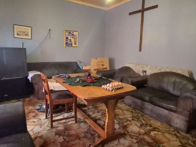 A living room space featuring carpet flooring and coving, currently requiring cosmetic updates to improve the overall condition and aesthetic appeal.