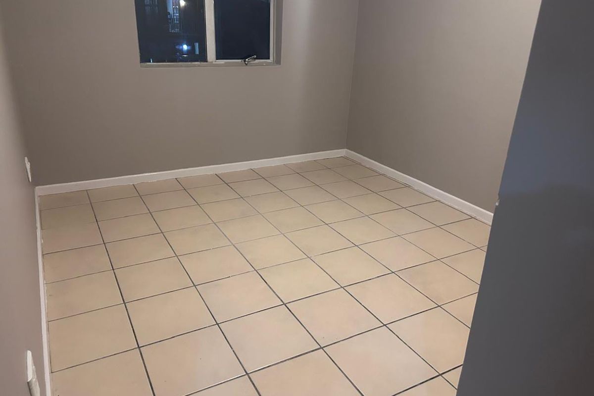 An empty bedroom featuring neutral wall paint and tiled flooring, providing a blank canvas for personalization.