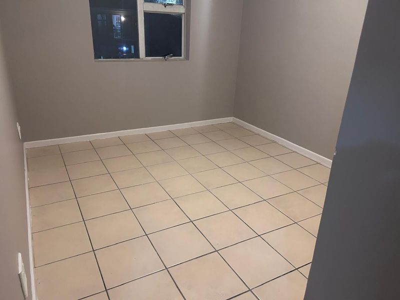 An empty bedroom featuring neutral wall paint and tiled flooring, providing a blank canvas for personalization.
