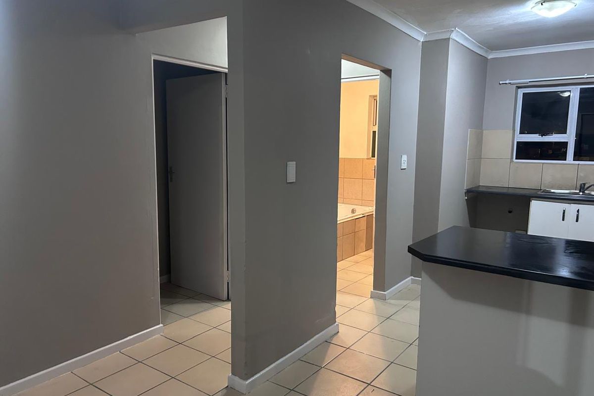 Open plan living area featuring tiled flooring, kitchen cabinetry with laminate countertops, and direct access to a bathroom and additional room.
