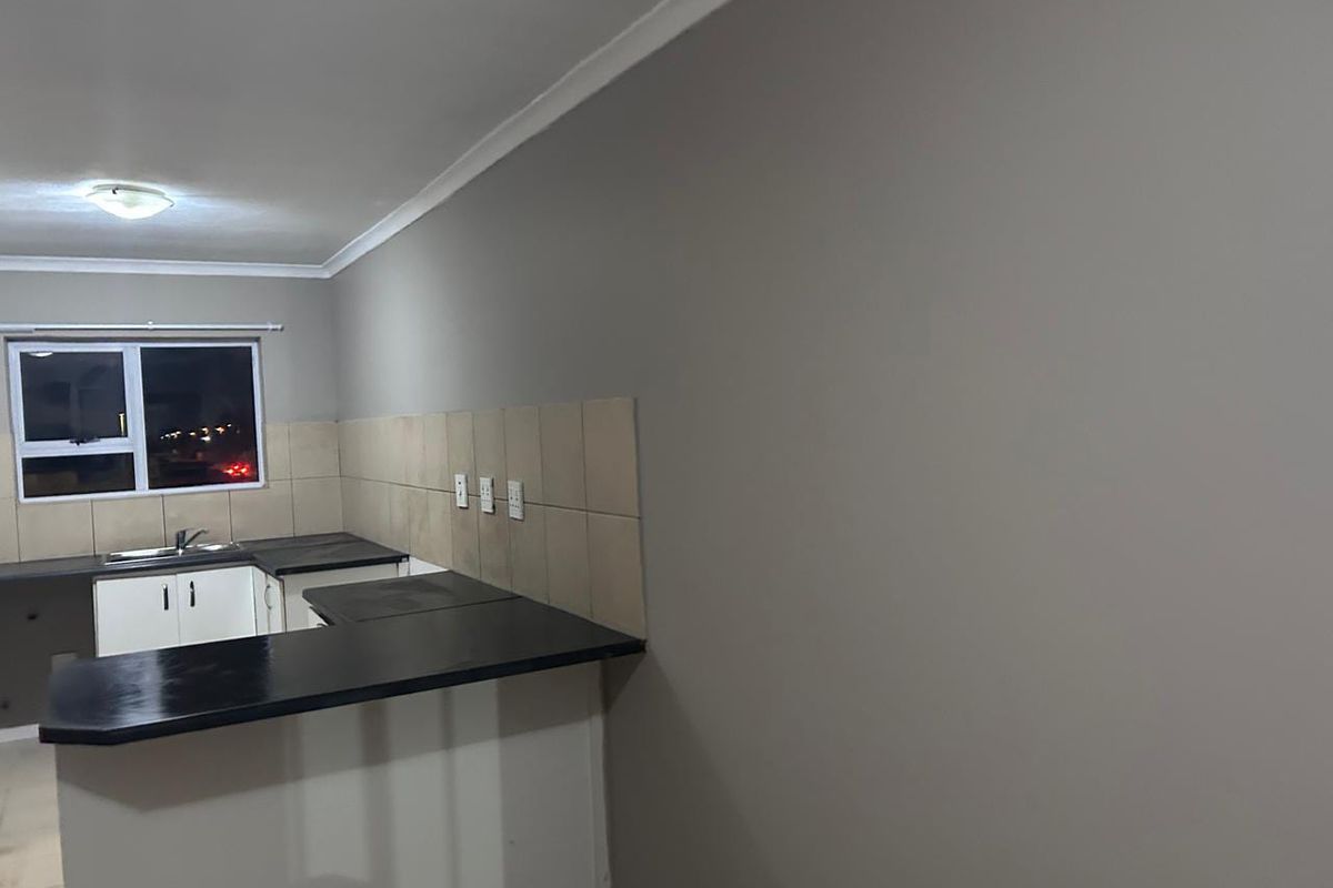 A functional kitchen area featuring dark countertops, white cabinetry, and a tiled backsplash, presented in a clean, empty state ready for personalization.