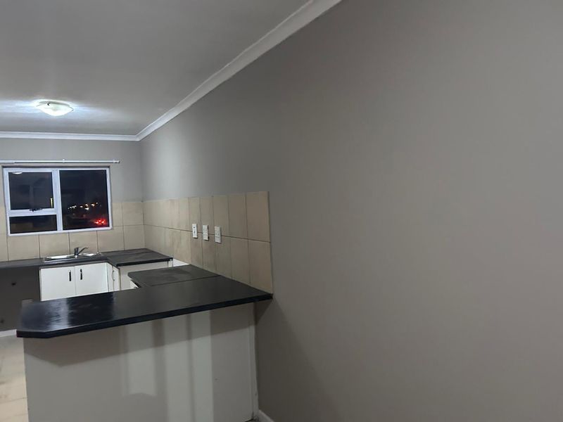 A functional kitchen area featuring dark countertops, white cabinetry, and a tiled backsplash, presented in a clean, empty state ready for personalization.