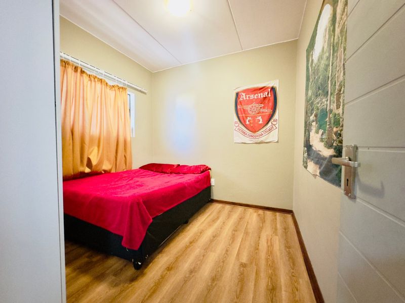 A functional bedroom featuring laminate flooring and neutral wall finishes, providing a comfortable space for rest.