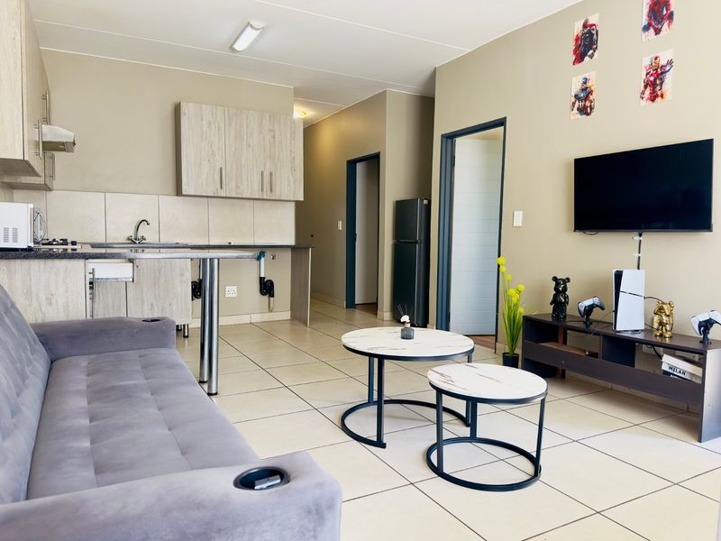 Open plan living area featuring a functional kitchen with laminate cabinetry, tiled flooring, and direct access to adjacent rooms.