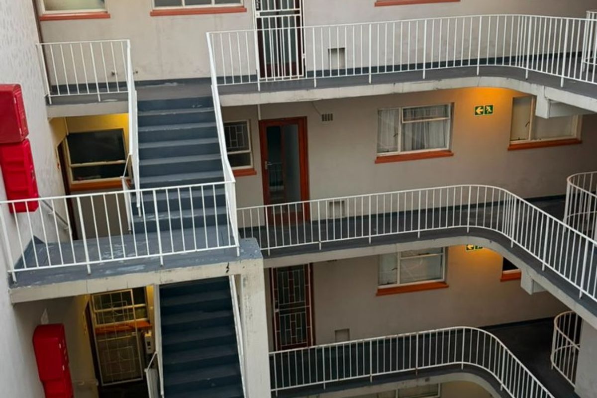 View of an apartment building central courtyard featuring external staircases, metal safety railings, and multiple access points to residential units.