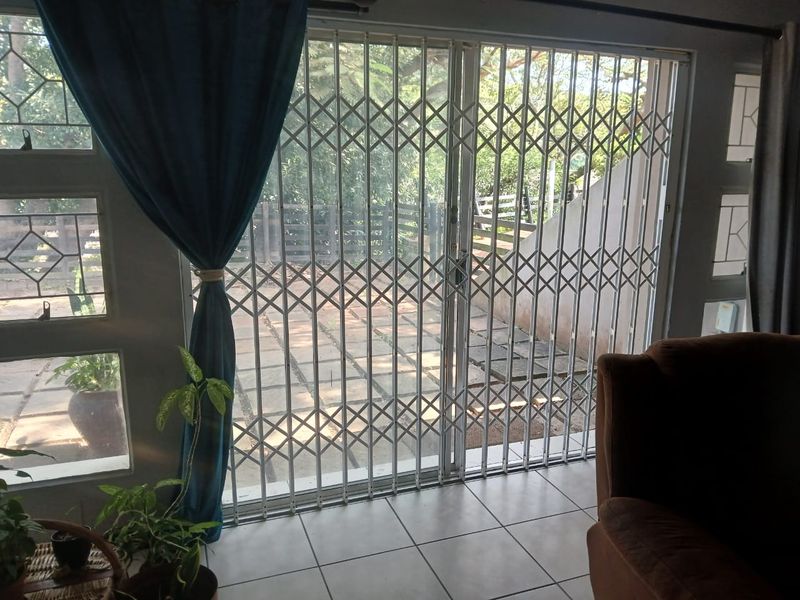 Living area featuring tiled flooring and a sliding glass door with a security gate, providing direct access to the outdoor patio area.