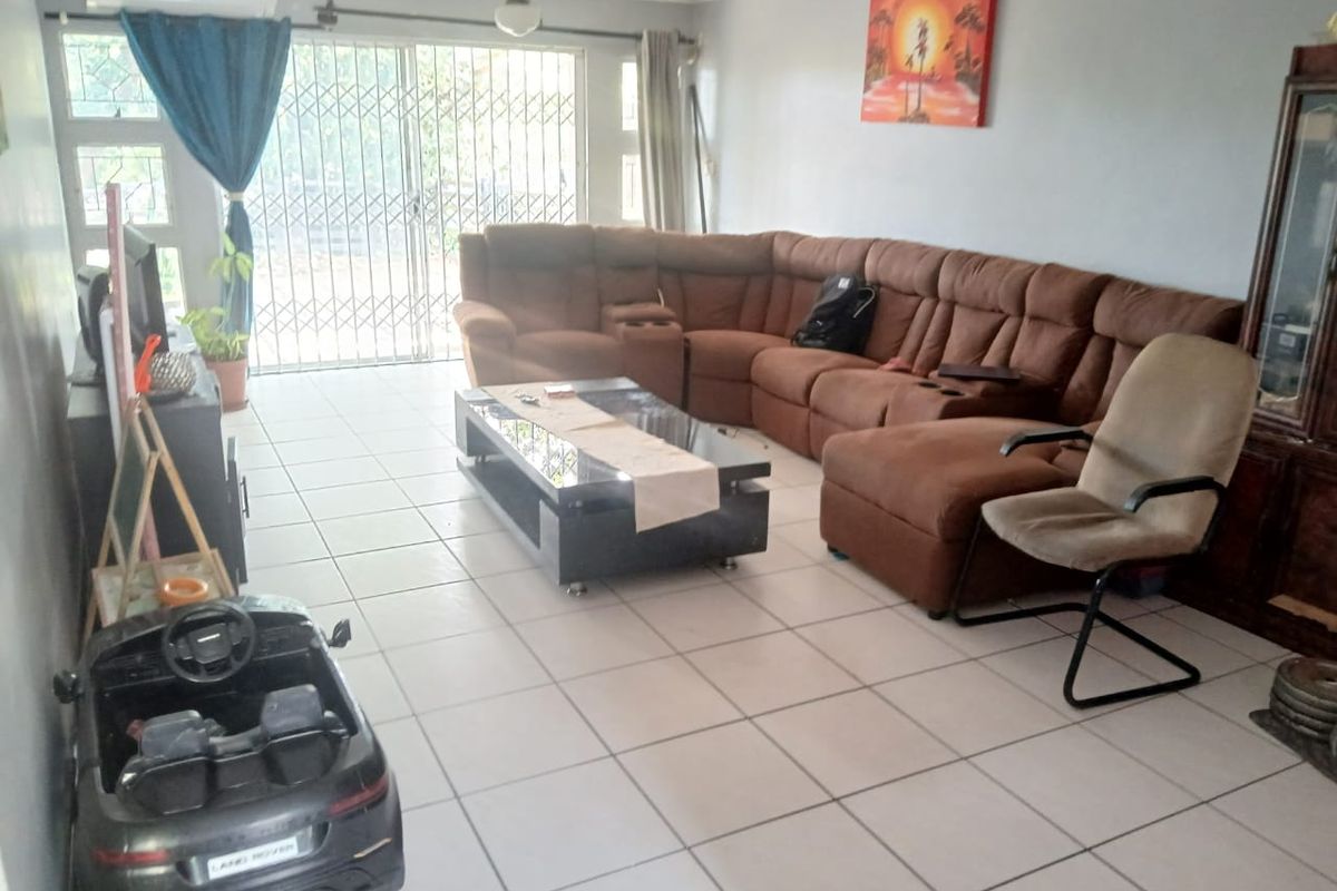 Spacious living room featuring tiled flooring, a ceiling fan, split-system air conditioning, and a sliding glass door with security gate access to the exterior.