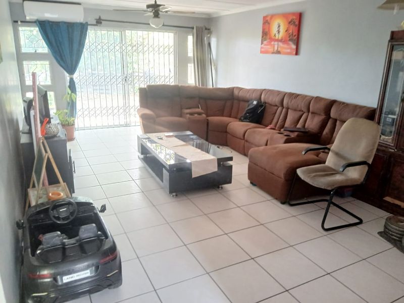 Spacious living room featuring tiled flooring, a ceiling fan, split-system air conditioning, and a sliding glass door with security gate access to the exterior.