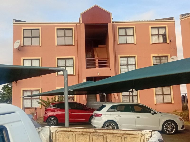 Front elevation of a multi-story apartment building featuring a central stairwell, balcony access, and dedicated shade cloth parking bays.