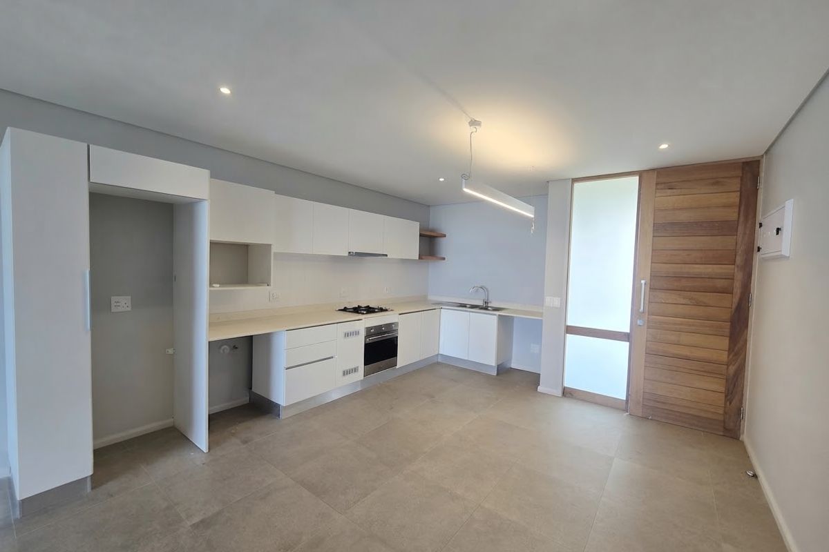 Modern kitchen featuring white cabinetry, built-in gas hob, oven, and tiled flooring, adjacent to a timber entrance door in an open-plan layout.