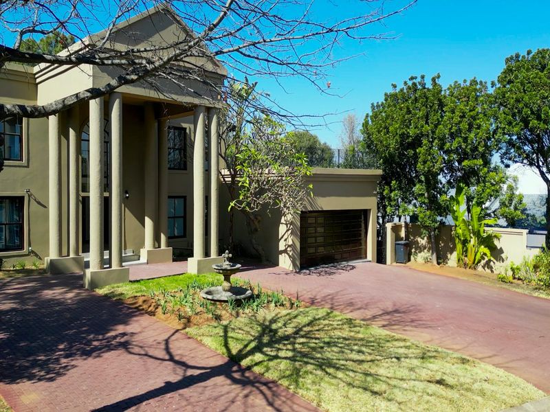 Front elevation of a stately home featuring a paved driveway, double garage, and an impressive portico with classical columns.