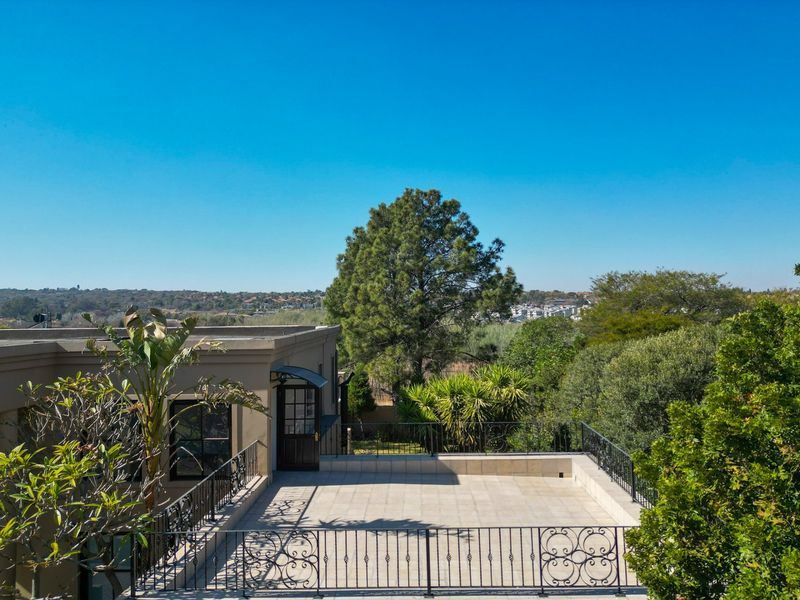 Spacious elevated terrace featuring tiled flooring and decorative wrought iron railings, offering expansive views of the surrounding landscape.