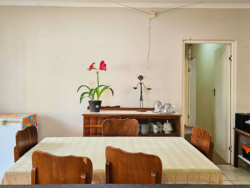 A dining area featuring tiled flooring and coving, with visible wall scuffs and exposed electrical wiring requiring attention.