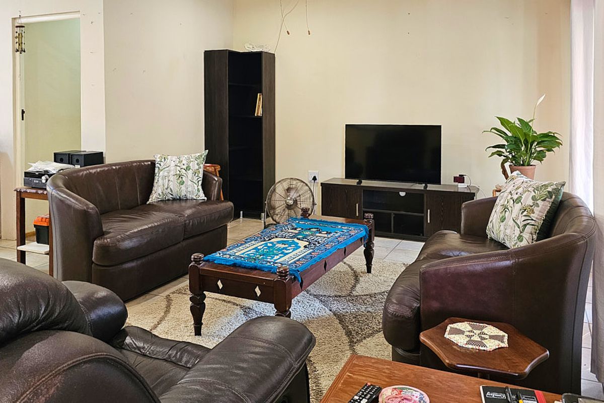 A living room featuring tiled flooring and neutral wall finishes, currently showing signs of wear and exposed electrical wiring.
