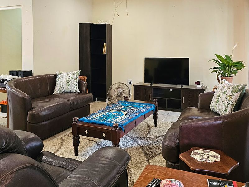 A living room featuring tiled flooring and neutral wall finishes, currently showing signs of wear and exposed electrical wiring.