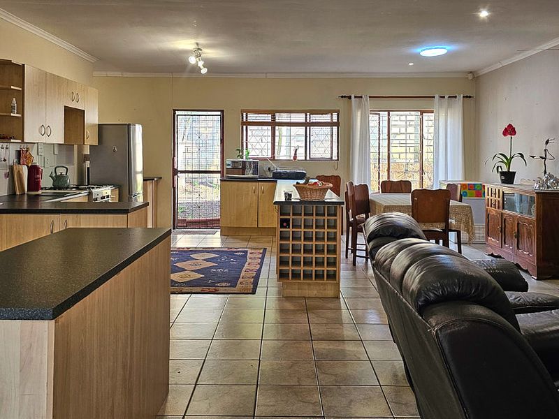 Spacious open-plan living and kitchen area featuring tiled flooring, ample built-in cabinetry, and a functional layout with direct access to the exterior.