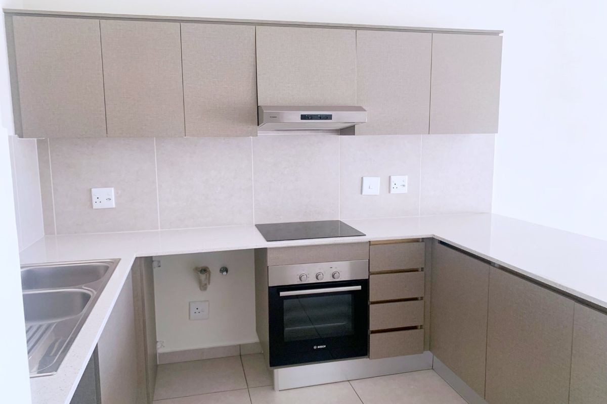 Modern kitchen featuring neutral cabinetry, stone countertops, integrated oven and hob, and tiled backsplash. Space is ready for appliance installation.